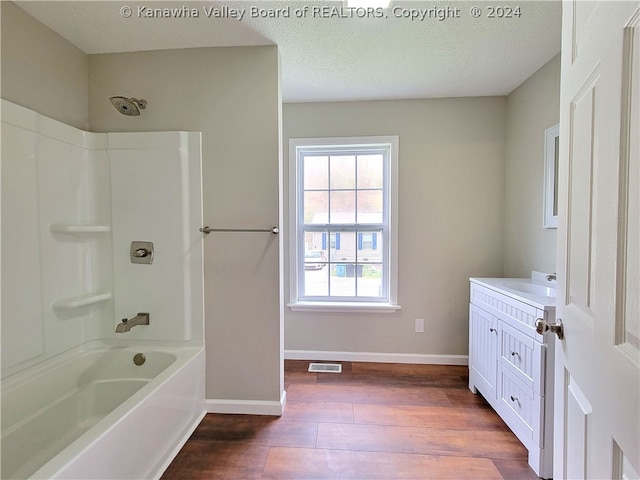 bathroom featuring vanity, hardwood / wood-style floors, shower / washtub combination, and a textured ceiling