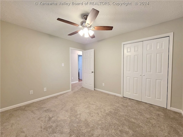 unfurnished bedroom featuring light carpet, ceiling fan, a closet, and a textured ceiling