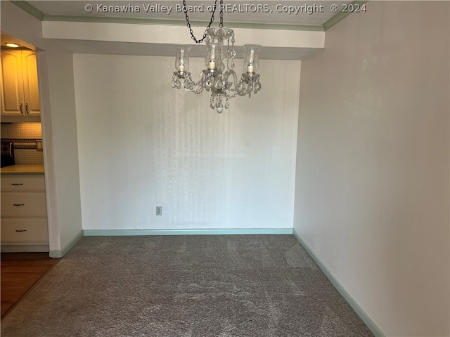 unfurnished dining area with a chandelier, carpet flooring, and ornamental molding