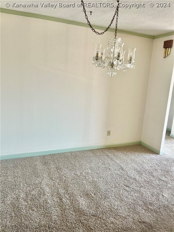 carpeted empty room featuring a textured ceiling and a notable chandelier