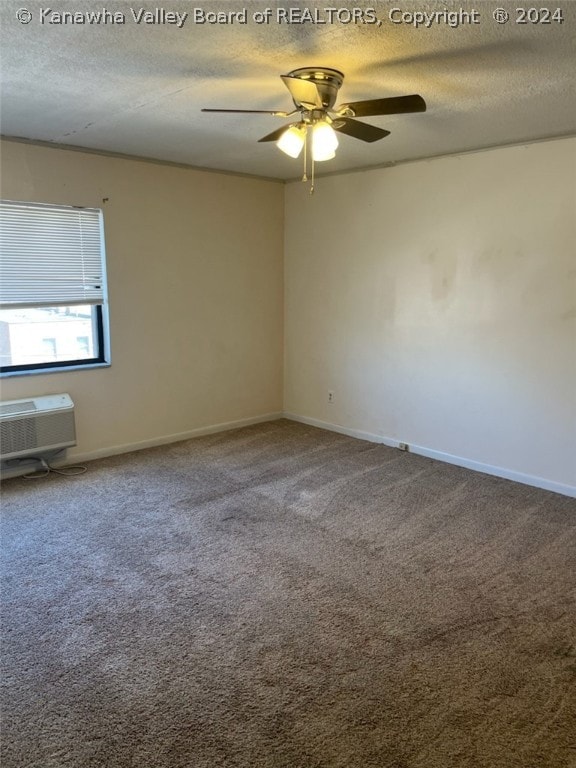 empty room featuring ceiling fan, carpet flooring, a wall unit AC, and a textured ceiling