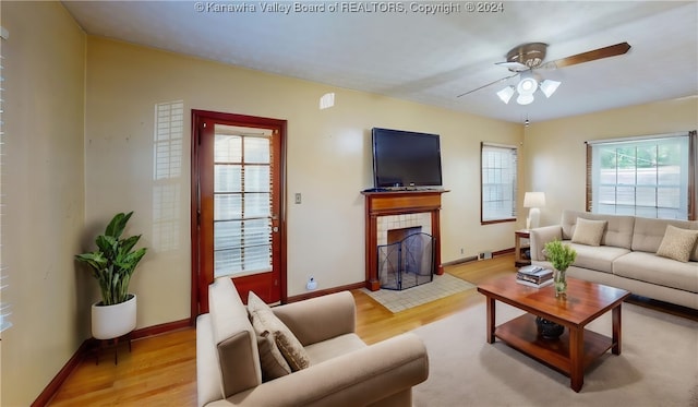 living room with light hardwood / wood-style floors, ceiling fan, and a fireplace