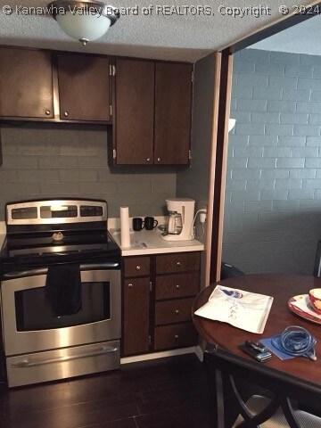 kitchen with dark brown cabinets, stainless steel range with electric stovetop, dark hardwood / wood-style floors, and a textured ceiling