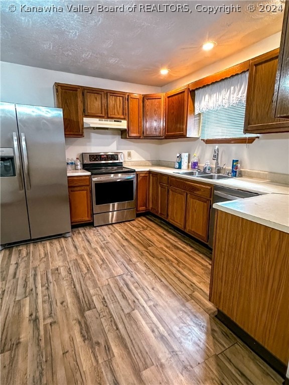 kitchen with hardwood / wood-style flooring, appliances with stainless steel finishes, a textured ceiling, and sink