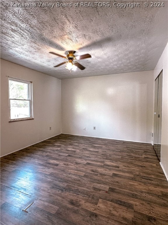 empty room featuring dark hardwood / wood-style flooring, ceiling fan, and a textured ceiling