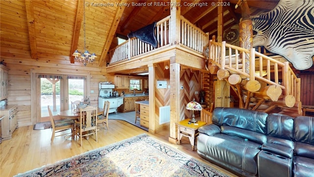 living room with a notable chandelier, wood walls, beam ceiling, and hardwood / wood-style flooring