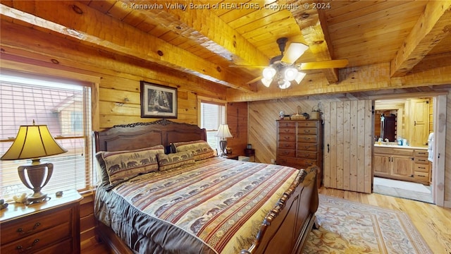 bedroom with light hardwood / wood-style floors, wooden ceiling, beamed ceiling, wooden walls, and ensuite bath