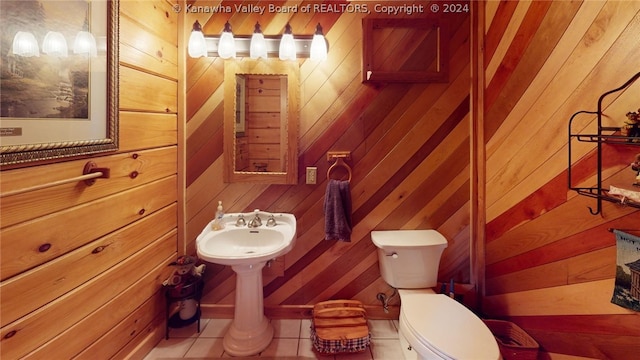 bathroom with tile floors, wooden walls, and toilet