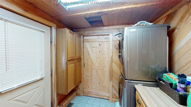 laundry area featuring cabinets, stacked washer and clothes dryer, wood walls, wood ceiling, and light tile floors