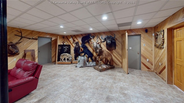 workout room with tile flooring, wooden walls, and a drop ceiling