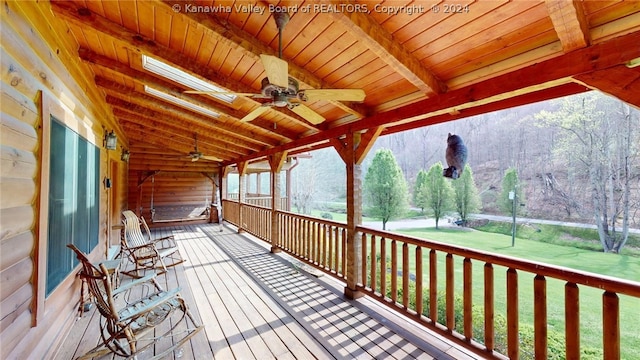 wooden terrace featuring a lawn and ceiling fan