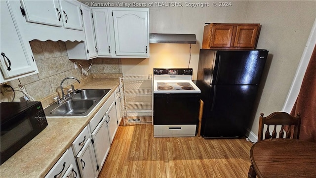 kitchen featuring black refrigerator, wall chimney exhaust hood, sink, white electric range, and white cabinetry