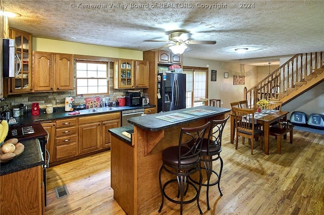 kitchen featuring sink, tasteful backsplash, light hardwood / wood-style flooring, appliances with stainless steel finishes, and a kitchen island