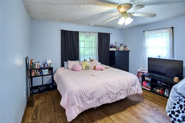 bedroom with multiple windows, wood-type flooring, and ceiling fan