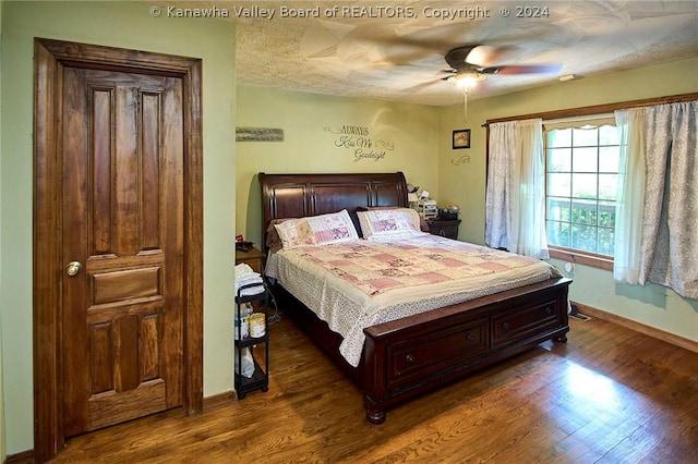 bedroom featuring dark hardwood / wood-style flooring, ceiling fan, and a textured ceiling