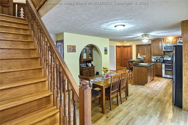 dining area with ceiling fan, light hardwood / wood-style flooring, and a textured ceiling