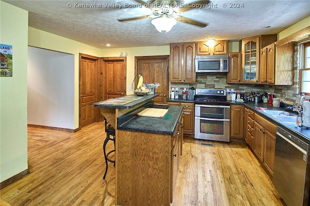 kitchen featuring a kitchen island, a breakfast bar, decorative backsplash, light hardwood / wood-style floors, and stainless steel appliances