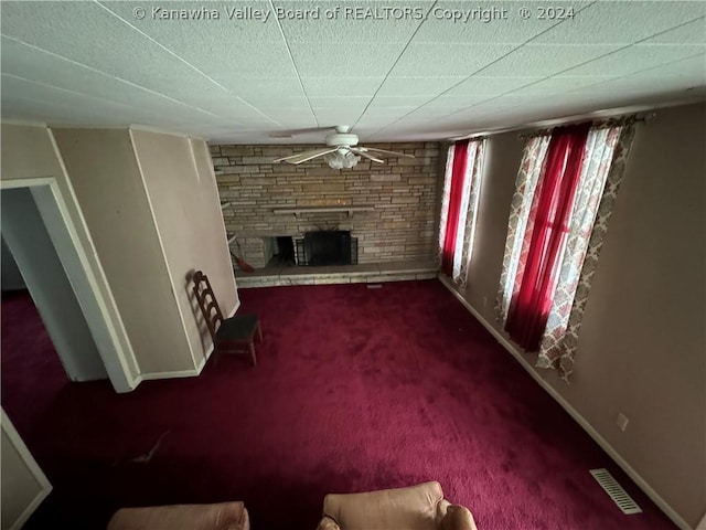 unfurnished living room with carpet, a stone fireplace, and ceiling fan