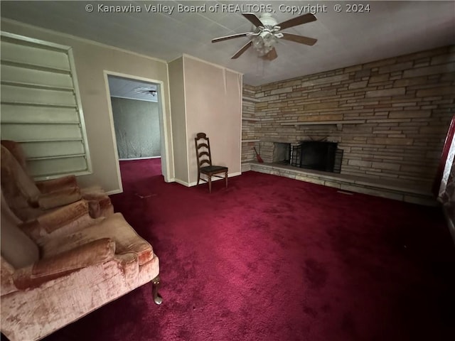 carpeted living room featuring a stone fireplace and ceiling fan