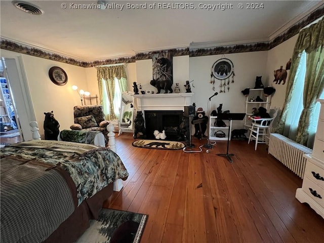 bedroom featuring radiator heating unit, ornamental molding, and wood-type flooring