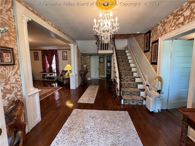 entrance foyer with dark wood-type flooring, decorative columns, and a notable chandelier