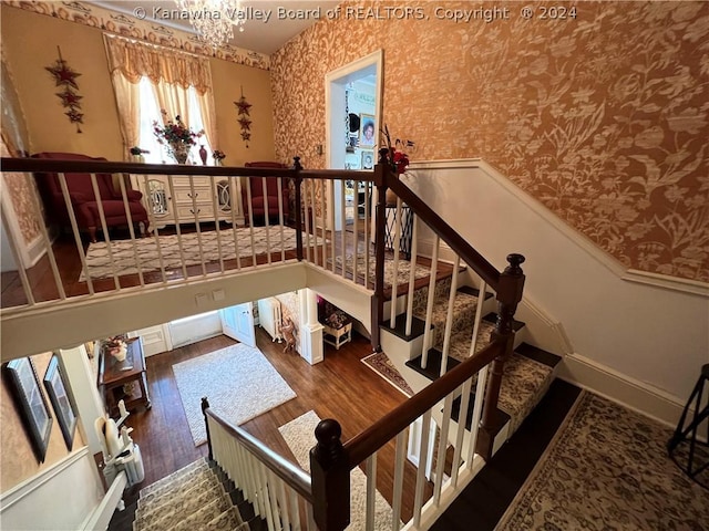 stairway featuring hardwood / wood-style floors and an inviting chandelier