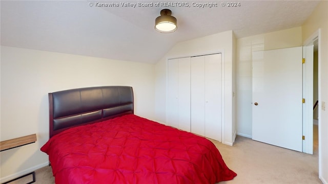 bedroom featuring a closet, light carpet, and vaulted ceiling