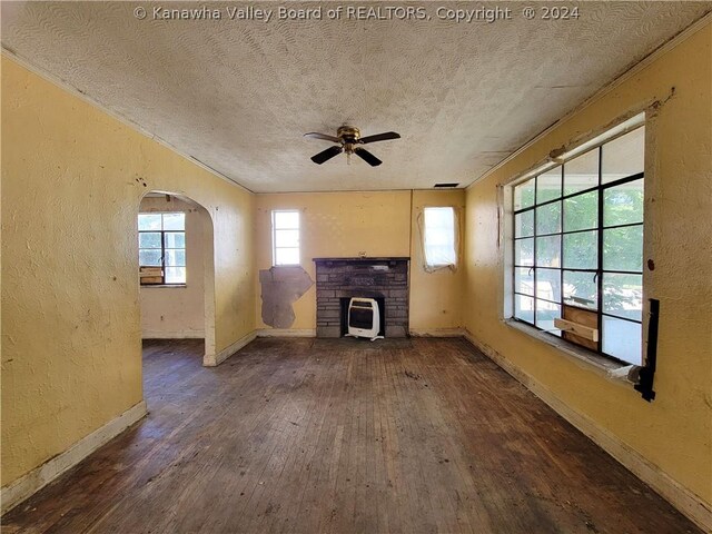 unfurnished living room featuring ceiling fan, a fireplace, a textured ceiling, and dark wood-type flooring