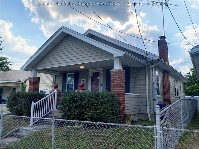 bungalow-style house featuring covered porch and a front yard