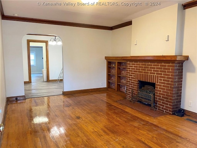 unfurnished living room featuring hardwood / wood-style floors, a brick fireplace, and ornamental molding