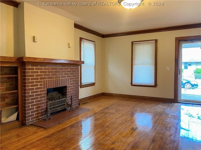 unfurnished living room with hardwood / wood-style flooring, a brick fireplace, and ornamental molding