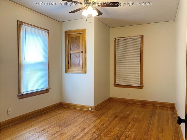 empty room with ceiling fan, crown molding, and light wood-type flooring