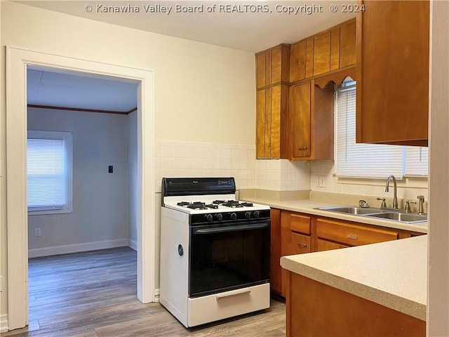 kitchen featuring sink, backsplash, gas stove, and light hardwood / wood-style floors