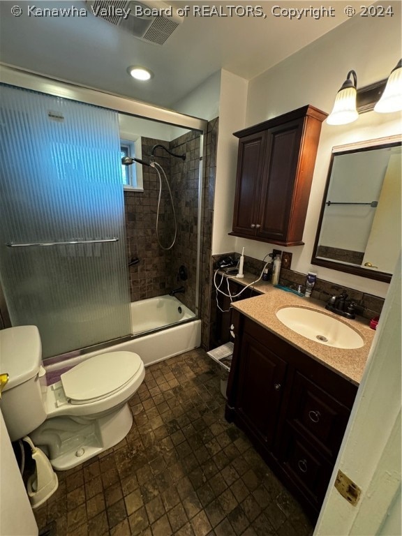 full bathroom featuring tile patterned flooring, bath / shower combo with glass door, toilet, and vanity