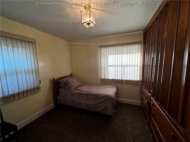 bedroom with dark colored carpet and a textured ceiling