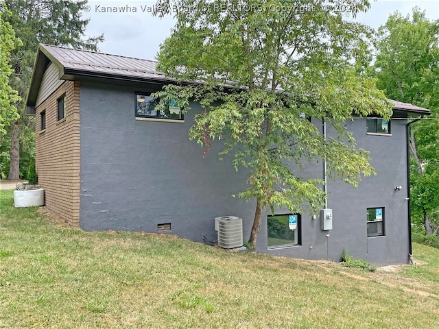 view of side of property featuring central AC unit and a yard