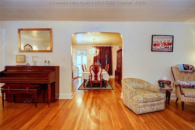 living area featuring hardwood / wood-style flooring, ornamental molding, and a chandelier