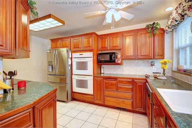 kitchen with sink, stainless steel fridge, white double oven, ceiling fan, and light tile patterned flooring