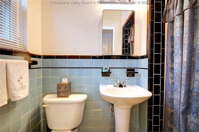 bathroom featuring tile walls and toilet