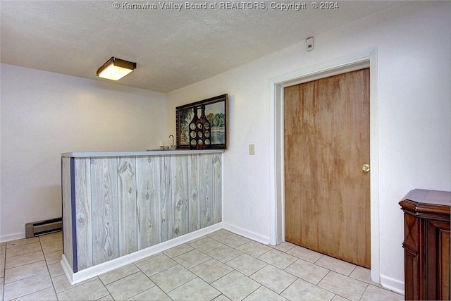 interior space with indoor bar, a textured ceiling, and baseboard heating