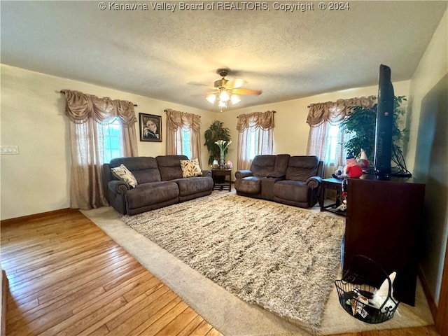 living room featuring ceiling fan, a textured ceiling, wood-type flooring, and a healthy amount of sunlight