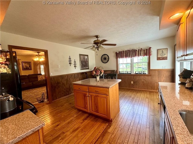 kitchen featuring light wood-type flooring, light stone countertops, a textured ceiling, and a kitchen island