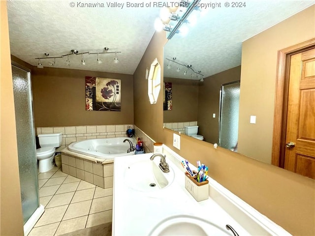 bathroom with tile patterned flooring, vanity, a relaxing tiled tub, toilet, and a textured ceiling