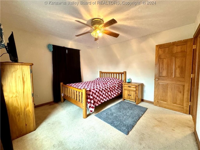 bedroom with ceiling fan, light carpet, and a textured ceiling