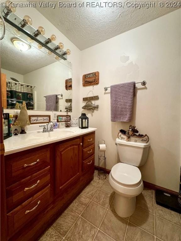 bathroom with vanity, a textured ceiling, tile patterned floors, and toilet