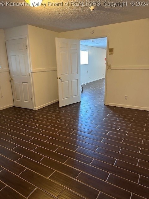 unfurnished room featuring a textured ceiling and dark hardwood / wood-style floors