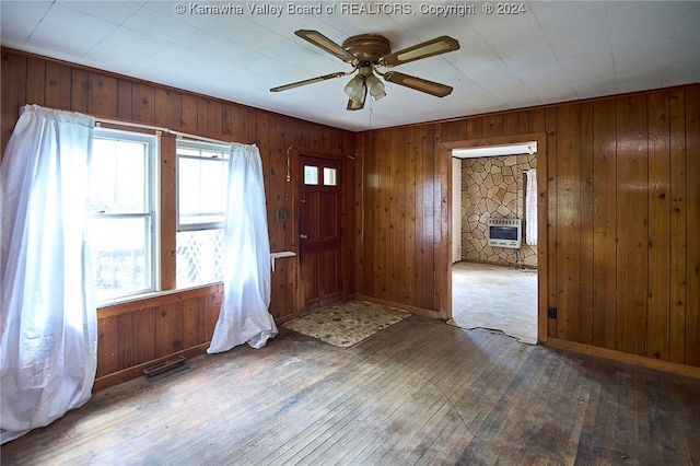 empty room featuring ceiling fan, wooden walls, and hardwood / wood-style floors