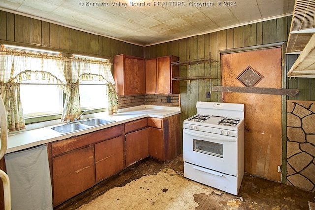 kitchen featuring wood walls, white gas stove, and sink