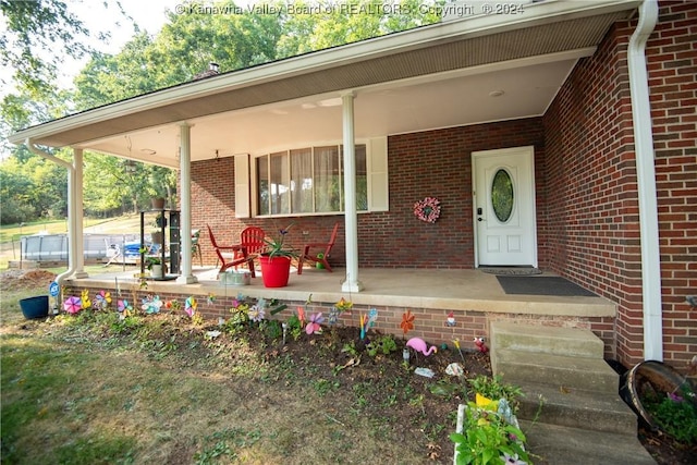 property entrance featuring covered porch and brick siding