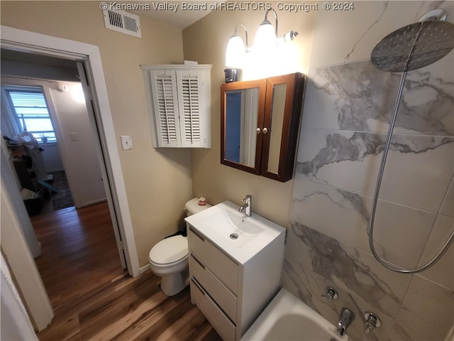 full bathroom featuring tiled shower / bath, toilet, vanity, hardwood / wood-style flooring, and vaulted ceiling